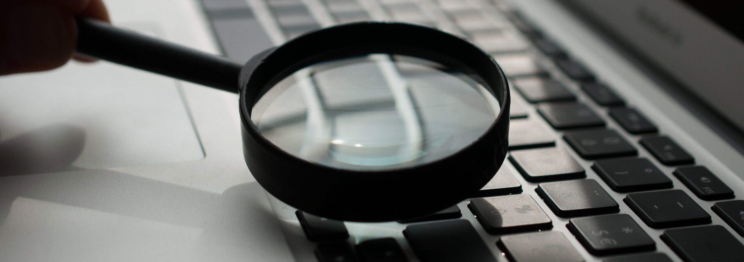 Magnifying glass held just above the keys of a laptop